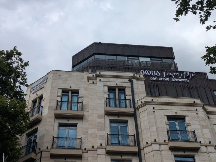 Гостиница в Тбилиси с вывесками в верхней части фасада и на торце здания